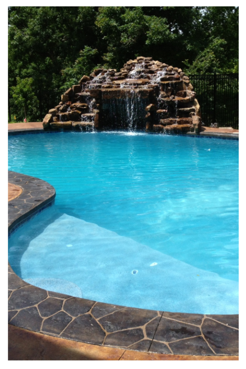 example of recent work, oblong curving pool with large fountain made of multiple rocks creating a naturalistic waterfall.