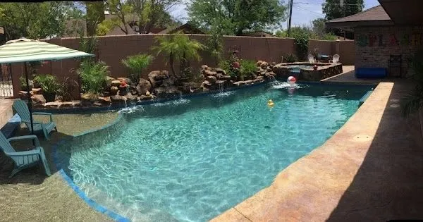 Long freeform pool with natural rock edging and landscaping