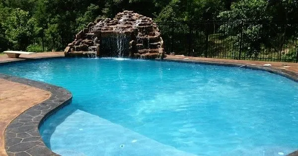Freeform pool with rock grotto waterfall and dark coping